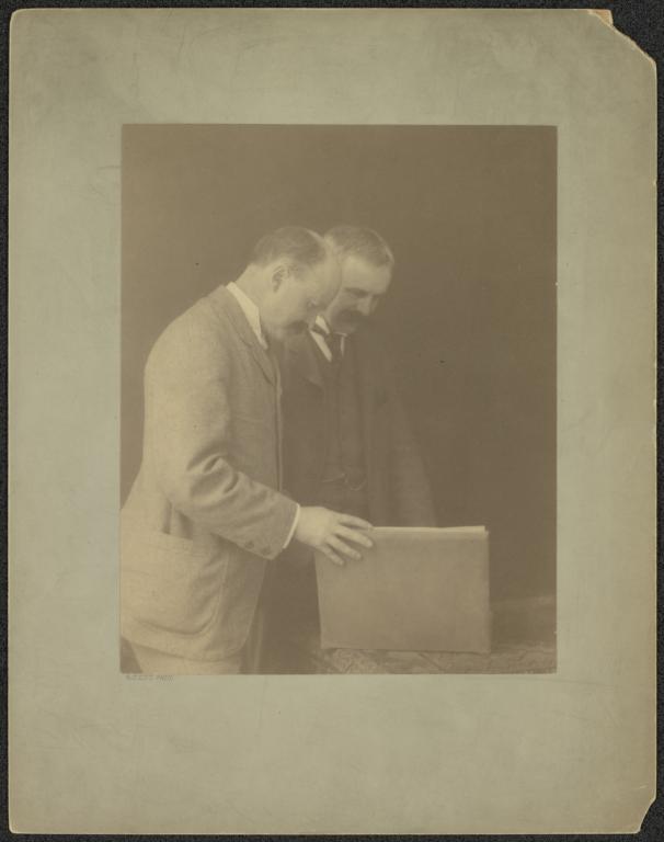 Charles Follen McKim and William Mead, standing, looking at book on table