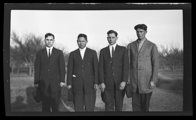 Four Men Standing in a Field Wearing Suits and Ties