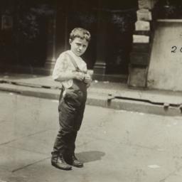 Boy in Overalls on Sidewalk